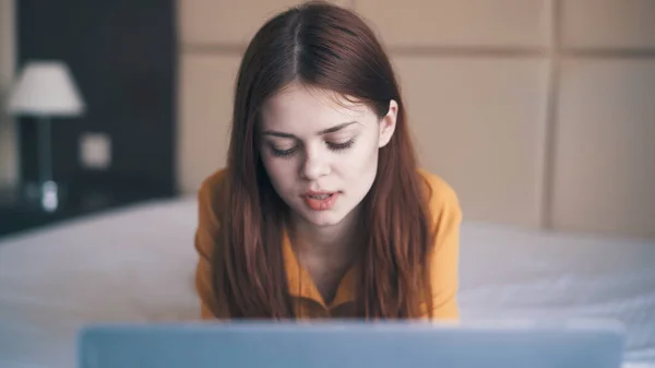 Dizüstü bilgisayarı olan güzel bir kadın internette yatıyor. — Stok fotoğraf