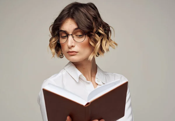 Mulher alfabetizada com livro nas mãos e em óculos modelo de educação camisa branca — Fotografia de Stock