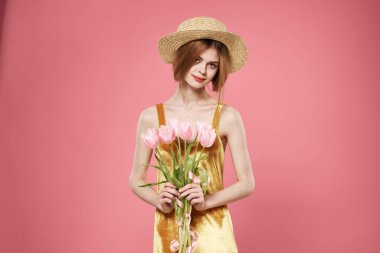 Güzel kadın altın elbise ve bir buket çiçek zarif, pembe arka plan