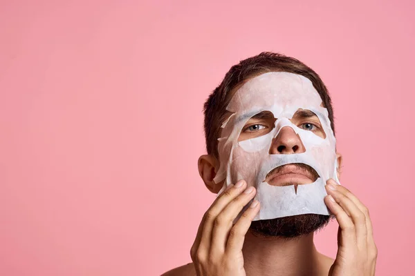 Homem com ombros nus limpar pele rosto cuidado rosa fundo — Fotografia de Stock