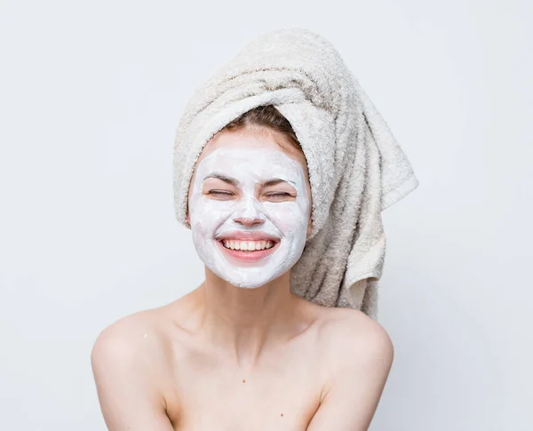 Mulher com ombros nus rosto toalha creme na cabeça — Fotografia de Stock