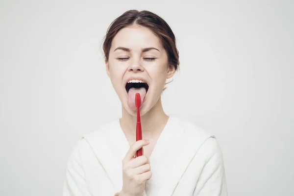 Pretty woman in white robe brushing tongue hygiene — Stock Photo, Image