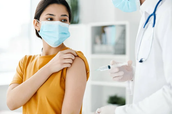 Un paciente en un hospital y un médico con guantes protectores inyectan una vacuna en el hombro de una mujer covid —  Fotos de Stock