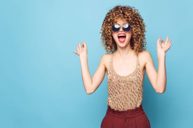 Güzel kadın, kıvırcık saçlı, komik jest, ruj sürmeli, pullu gömlek. 