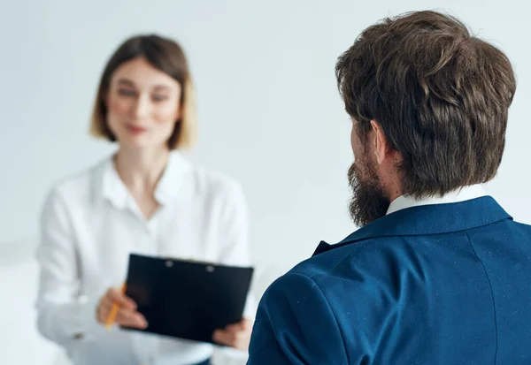 Un uomo con una giacca blu e una donna con una camicia documenta uno sfondo chiaro al coperto — Foto Stock