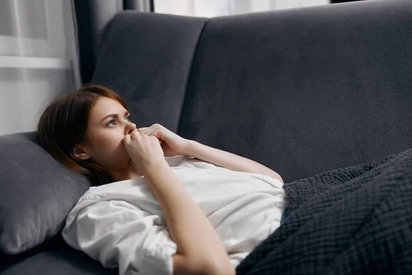 Kobieta z otwartymi oczami leży na szarej kanapie — Zdjęcie stockowe