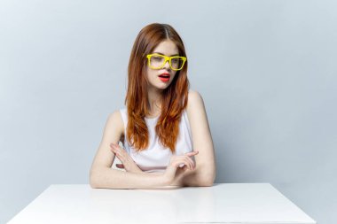 Masada oturan beyaz elbiseli güzel kadın. Sarı gözlükler. Duygular çekici.