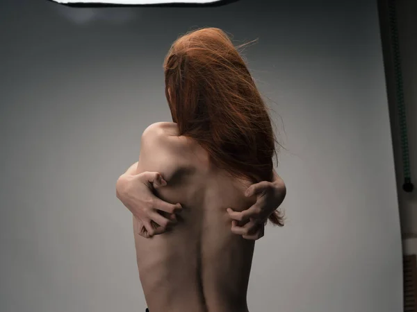 Nude woman touches herself behind her back with hands stress emotions red hair — Stock Photo, Image