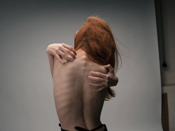 Szczupła kobieta dotyka się za plecami modelką emocji. — Zdjęcie stockowe