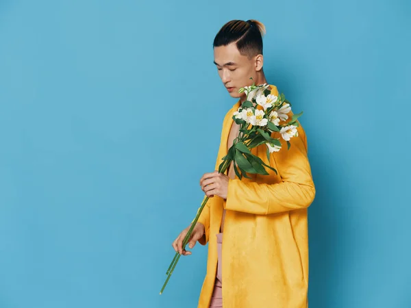 Homem na moda em um casaco amarelo segurando um buquê de flores brancas, modelo de aparência asiática — Fotografia de Stock