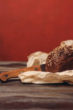 Kırmızı zemin üzerinde çavdar ekmeği ve keskin bıçaklı ahşap bir masa.