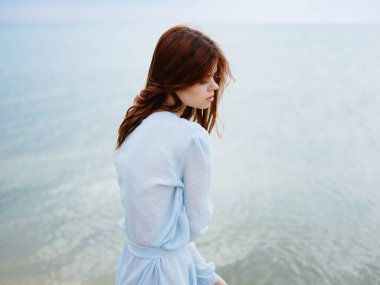 Sahilde deniz kenarında romantik kızıl saçlı bir kadının yakın çekim görüntüsü.