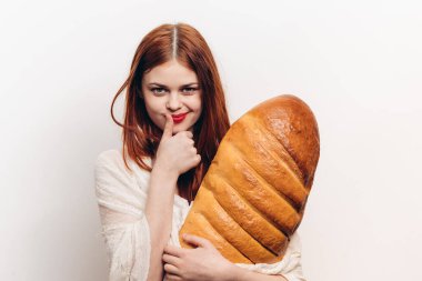 Ellerinde koca bir somun somunu olan, hafif arka planda şık giyinen duygusal bir kadın.