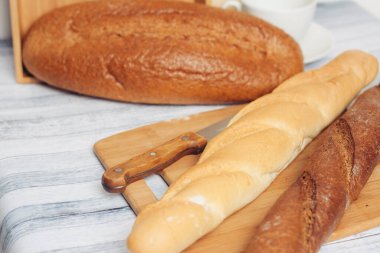 Ekmek sepetinde taze somunlar, masada kahvaltı. 