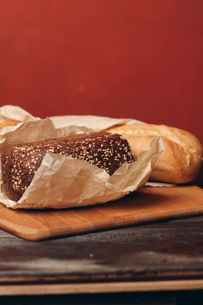Tahtada bir somun ekmek un ürünü ve kırmızı arkaplan — Stok fotoğraf