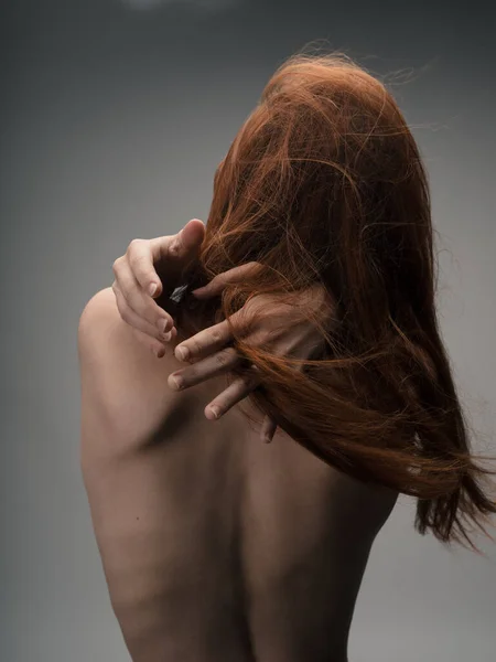 Вид на сексуальную рыжеволосую женщину с обнаженной спиной, касающуюся руками — стоковое фото