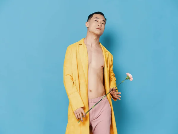 Homem sexy em calças rosa e um casaco desabotoado com uma flor na mão — Fotografia de Stock
