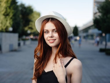 Siyah elbiseli şık bir kadın parkta, doğada yürüyor.