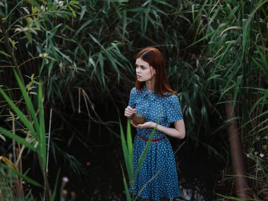 Yeşil çimenlerin yanında açık havada bir kadın ve arka planda bir nehir.