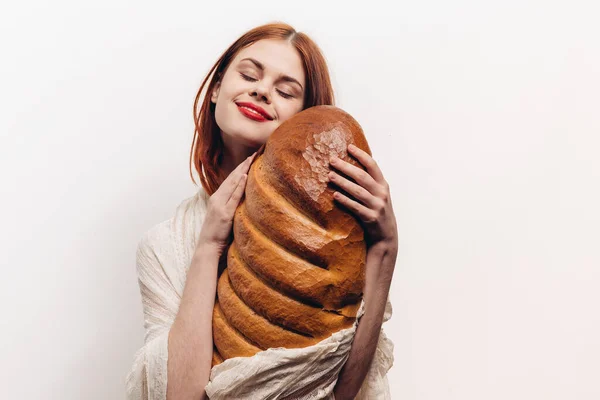 Donna abbraccia pane fresco con le mani su un leggero fondo di pane farina prodotti — Foto Stock