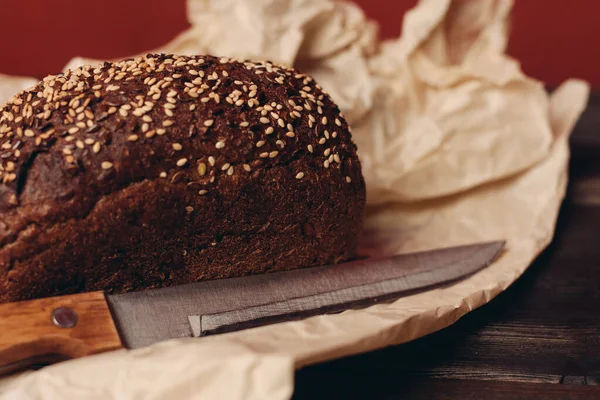 rye bread baking on paper packaging wooden table and sharp knife