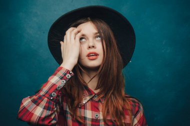Kafasında şapkası olan çekici bir kadın ve elleri ile hareket eden ekoseli bir gömlek.