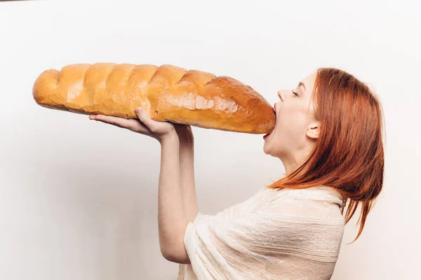 Donna affamata mangiare grande pane pane pagnotta vista laterale luce sfondo — Foto Stock