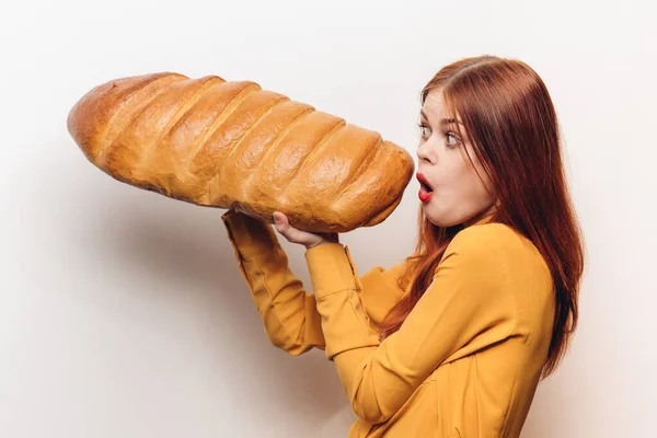 Mulher emocional com um enorme pão em um fundo leve divertido farinha produto — Fotografia de Stock