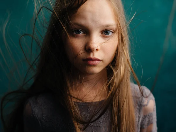 Dívka s chlupatými vlasy na tyrkysovém pozadí a šedé sluneční šaty — Stock fotografie