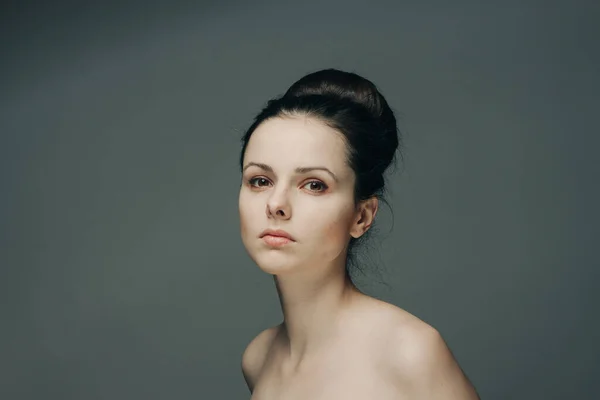 Mulher bonita com ombros nus em fundo cinza penteado modelo — Fotografia de Stock