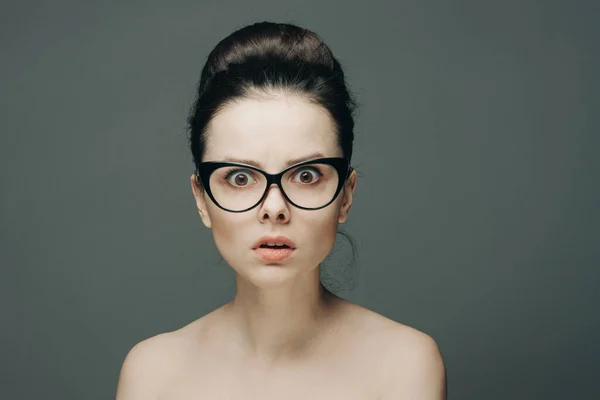 Überraschte Frau mit Brille nackte Schultern geraffte Haare grauen Hintergrund — Stockfoto