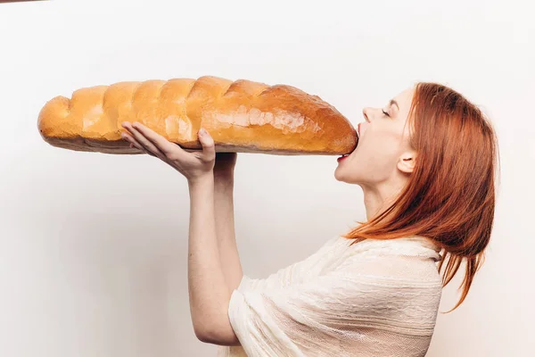 Mulher faminta comer pão grande pão de pão vista lateral luz fundo — Fotografia de Stock