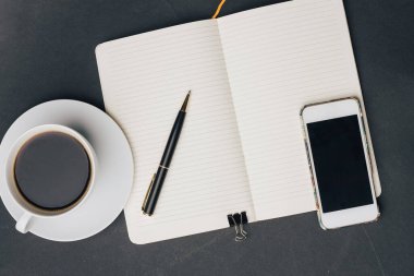 Masanın üzerinde kahve fincanı ve kalem telefon teknolojisi var.