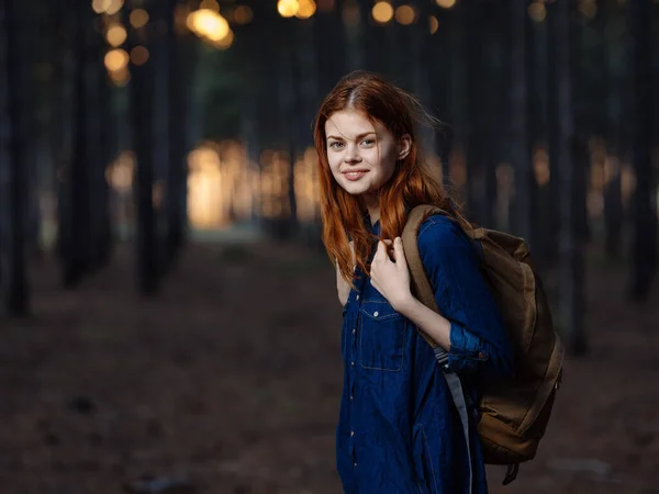 Mujer bonita viaja en el bosque con una mochila en la espalda y en una camisa azul —  Fotos de Stock