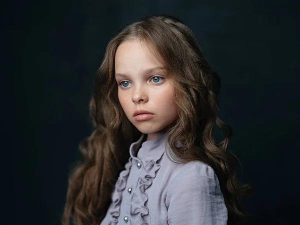 Portrét krásné dívky v šedých šatech na tmavém pozadí a kudrnaté vlasy modré oči — Stock fotografie