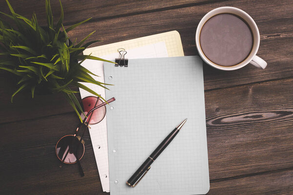 notebook and pen on a wooden table coffee cup flower in a pot top view
