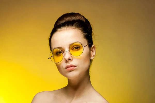 Красивая женщина голые плечи желтые очки эмоции очарование желтый фон — стоковое фото