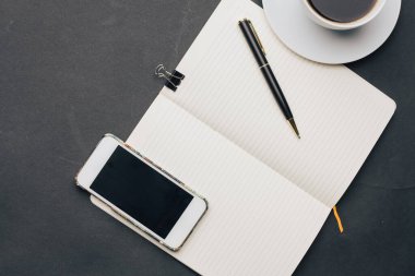 Masanın üzerinde kahve fincanı ve kalem telefon teknolojisi var.