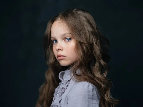 Portret pięknej dziewczyny w szarej sukience na ciemnym tle i kręcone włosy niebieskie oczy — Zdjęcie stockowe