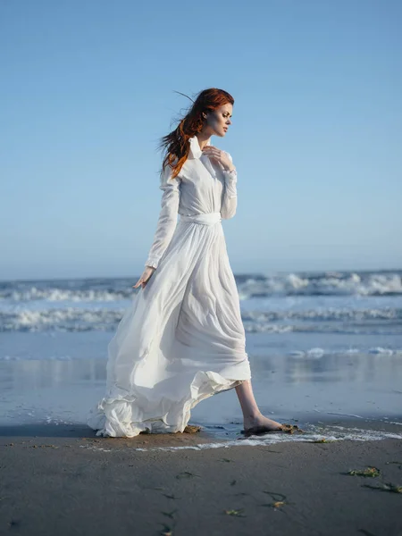 Γοητευτική γυναίκα με ένα φόρεμα κοντά στον ωκεανό στην ακτή της παραλίας μοντέλο κόκκινα μαλλιά — Φωτογραφία Αρχείου
