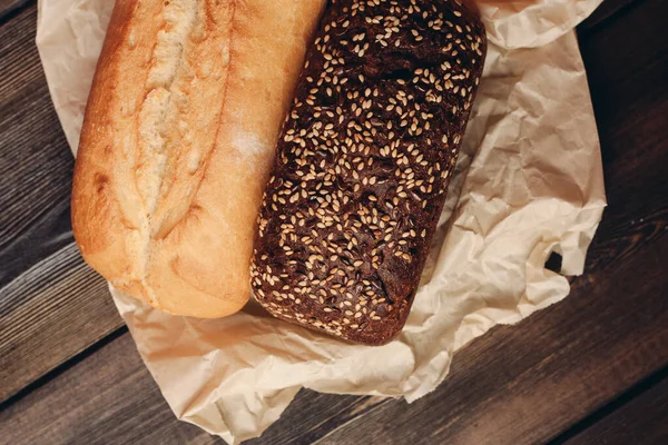 gray bread on paper packaging on wooden table and red background in the background kitchen knife