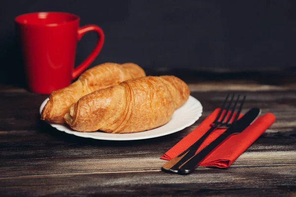 Färsk croissant på en tallrik köksredskap kaffekopp frukost — Stockfoto