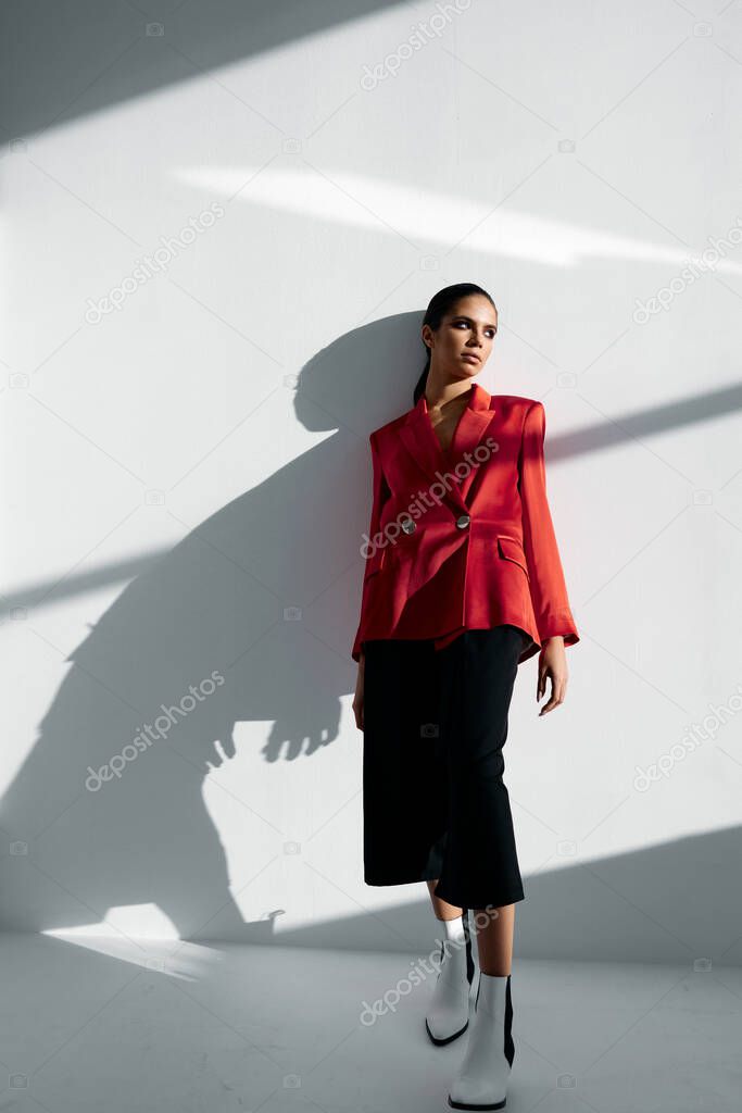 a woman in a fashionable suit is leaning against the wall in the room