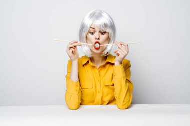 Masada oturan beyaz saçlı güzel kadın yemek çubukları diyet yemek stüdyosunda.