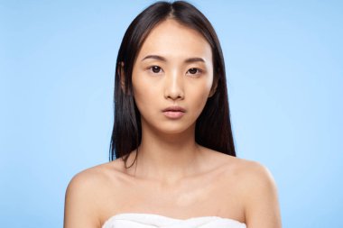 Çıplak omuzlu, Asyalı bir kadın. Temiz cilt bakımı mavi arka plan.