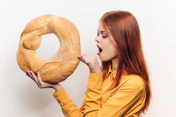 Woman with bright makeup holds a round loaf of bread in her hands on a light background Copy Space — Stock Photo, Image