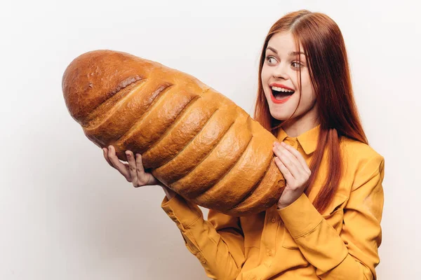 Retrato de una mujer feliz con un pan sobre un fondo claro y un maquillaje de camisa amarilla —  Fotos de Stock