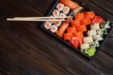 Suşi, ahşap bir masa ve yemek çubukları üzerinde deniz ürünleri ile yuvarlanır.
