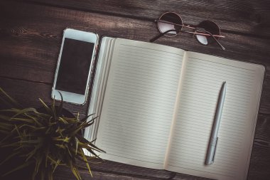 Kalem masası güneş gözlüğü telefon teknolojili defter.