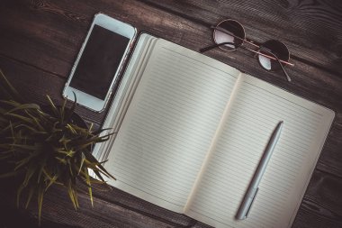 Kalem masası güneş gözlüğü telefon teknolojili defter.